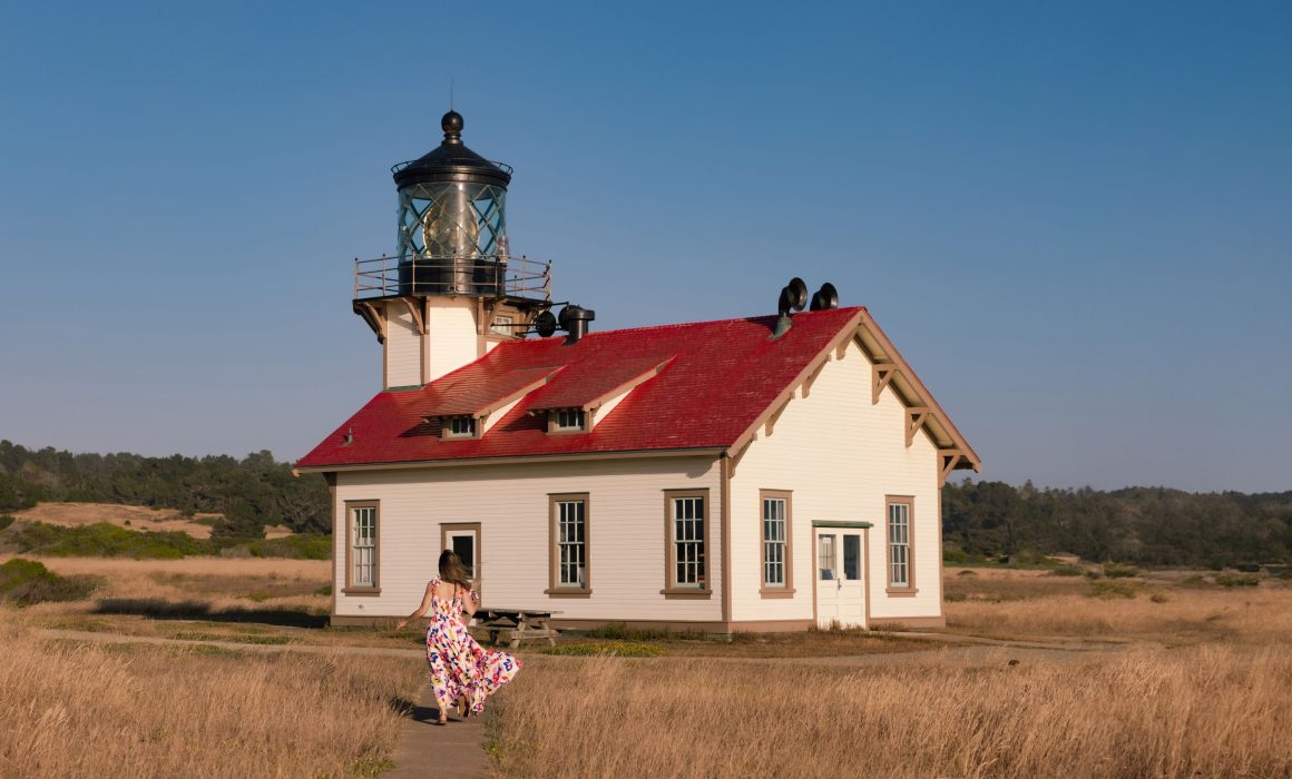The Point Cabrillo Lighthouse in Mendocino County, with a woman running down the path to it.