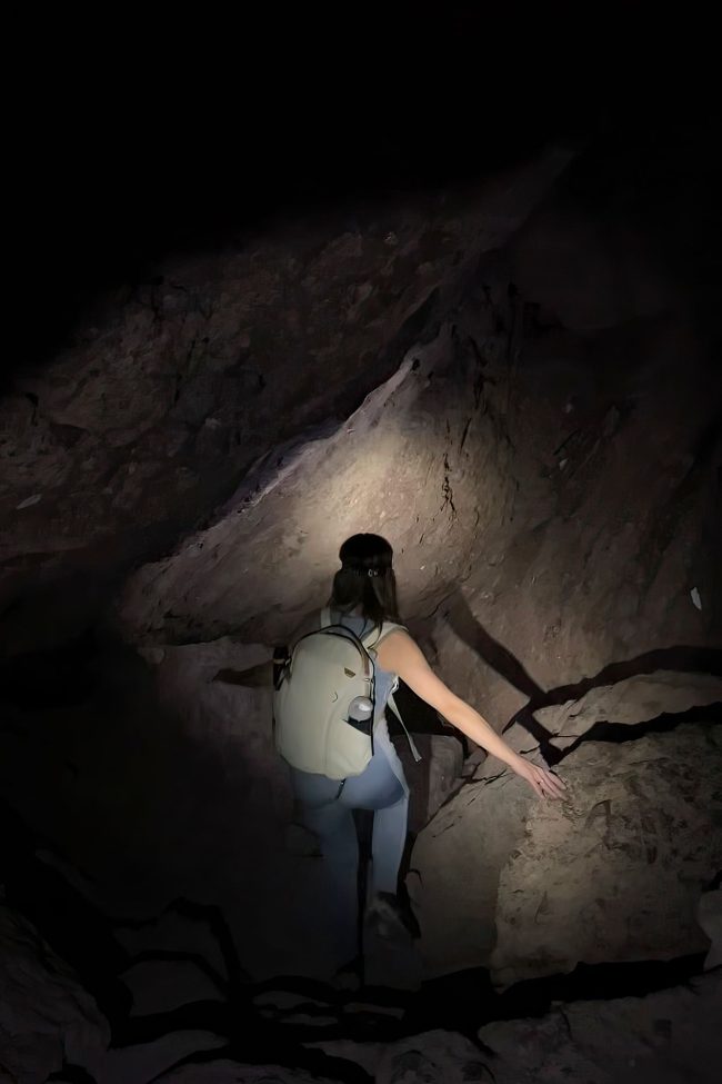 Person exploring the Bear Gulch Cave in darkness, lit only by a headlamp.