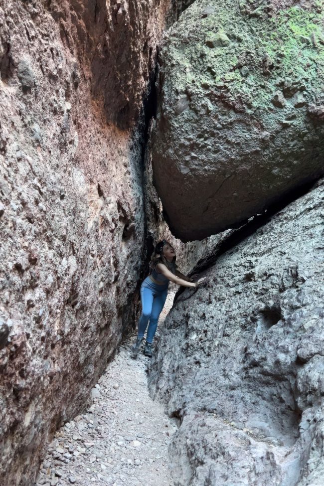 Person squeezing through the Bear Gulch Cave trail boulder openings.