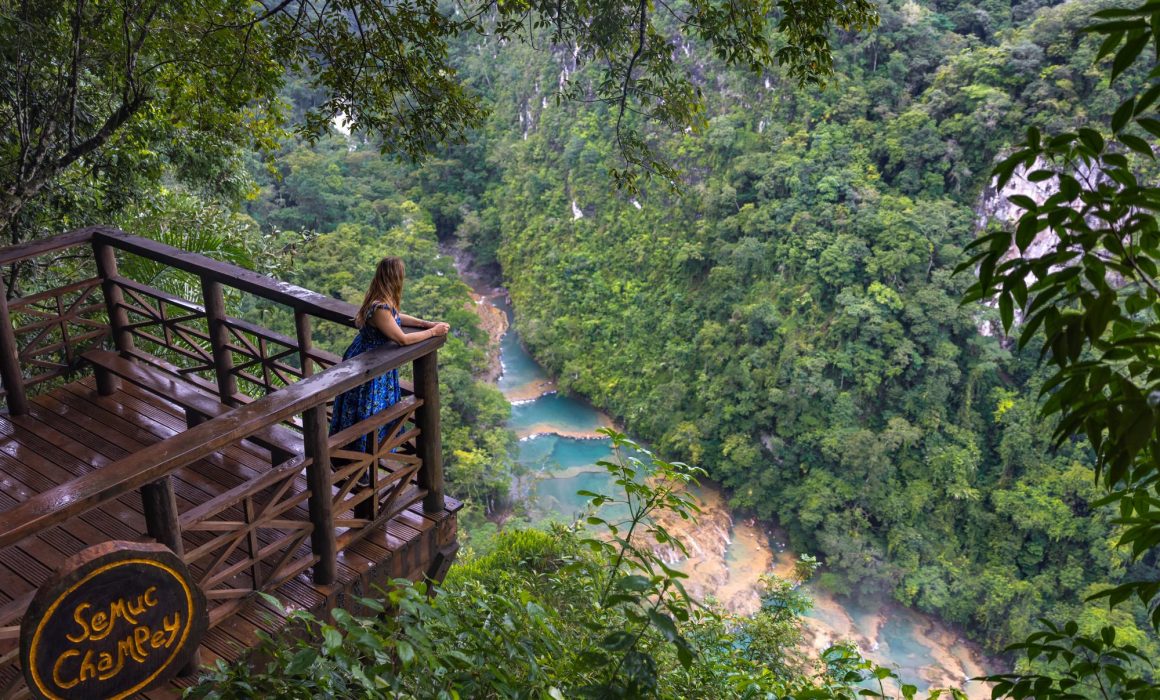 Woman looking over wooden railings towards Semuc Champey in Guatemala.