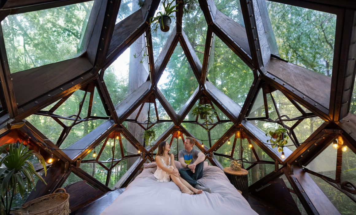 A couple lying on the bed inside the Pinecone Treehouse in California.