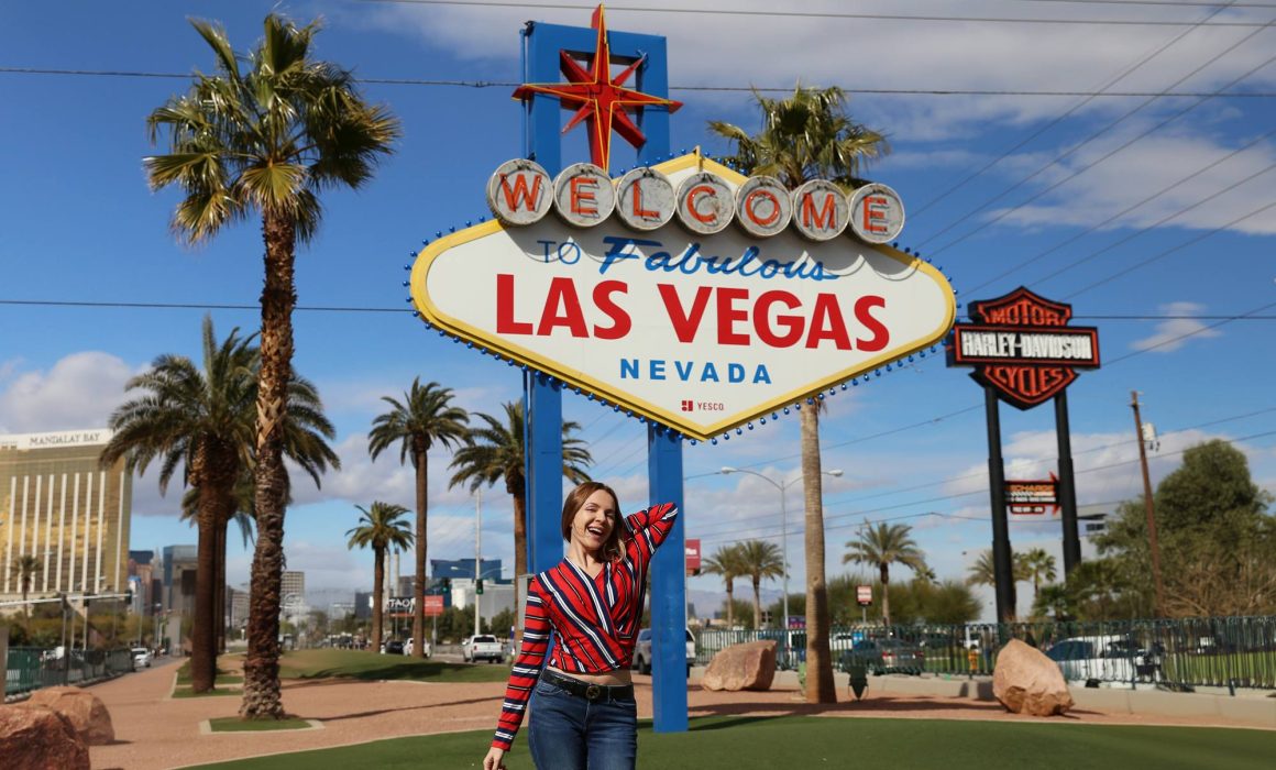 A sign saying Las Vegas in Las Vegas, Nevada, with a woman standing underneath.