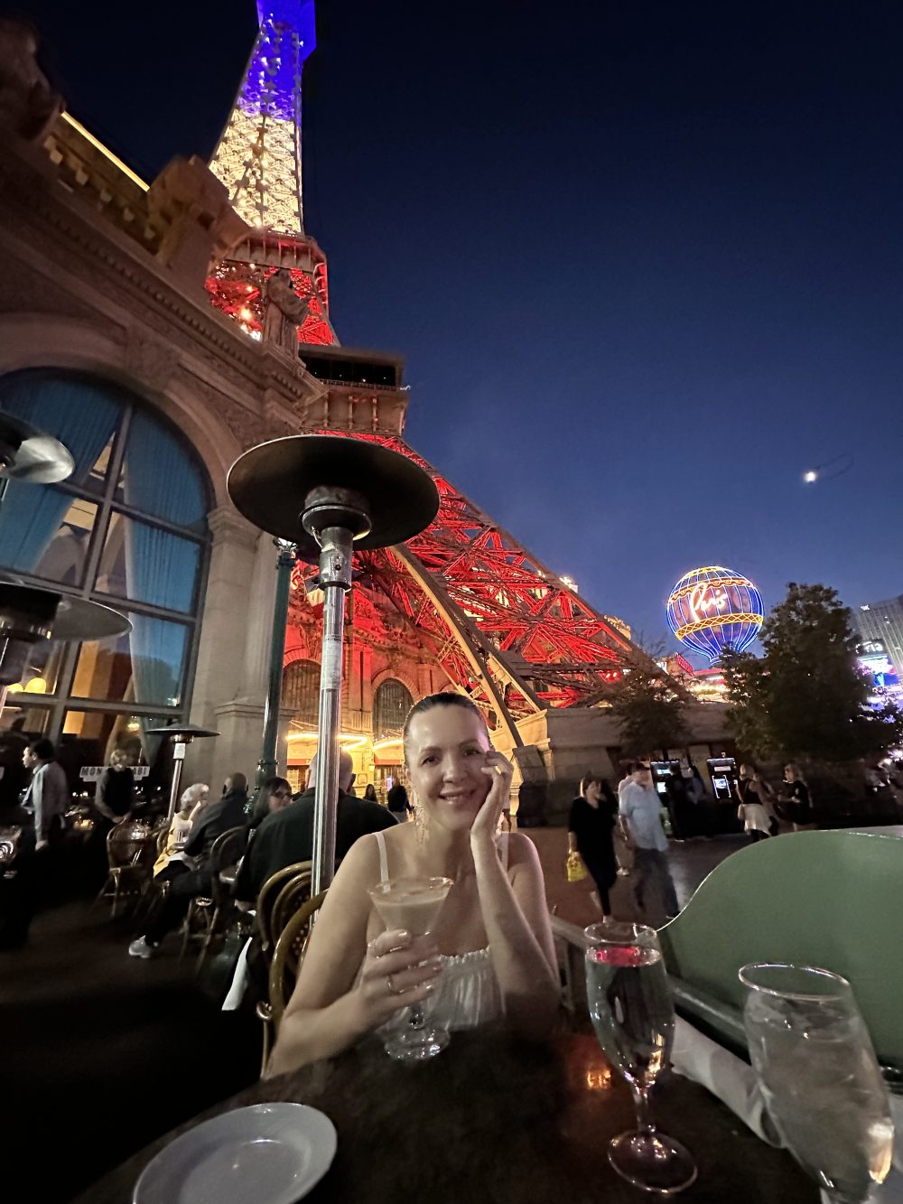 Woman eating under the Eiffel Tower in Paris Las Vegas at night.