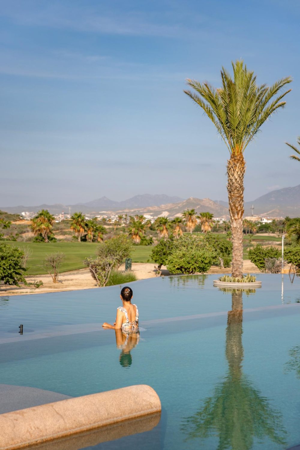 Woman standing in the main pool of Secrets Puerto, a resort in Los Cabos.