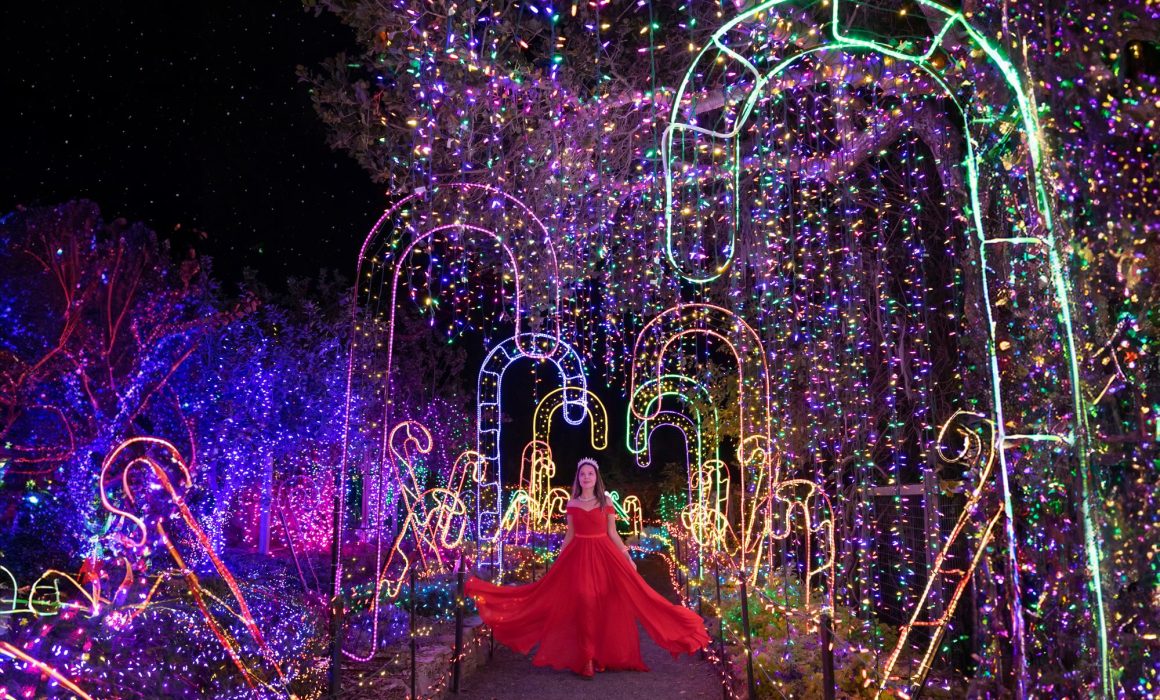 Woman in red dress walking through Christmas lights in California.